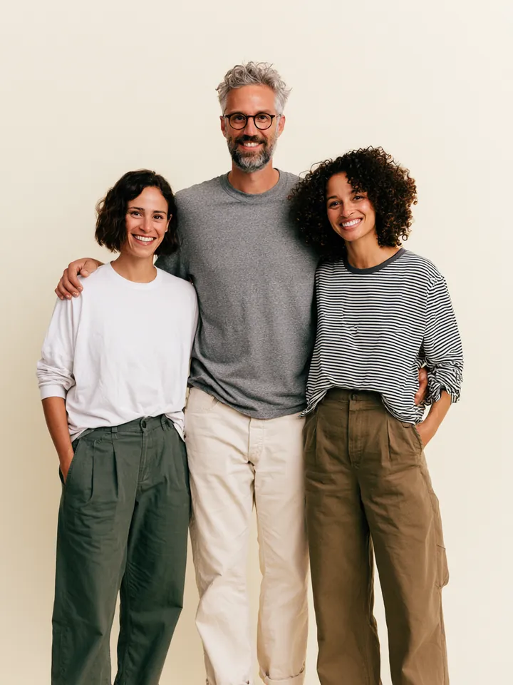 Three colleagues standing shoulder to shoulder in a pastel studio, the Happy Money Loan editorial and support team