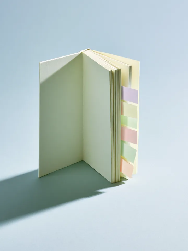 Open hardcover notebook standing upright with pastel sticky tabs, representing the Happy Money loan glossary