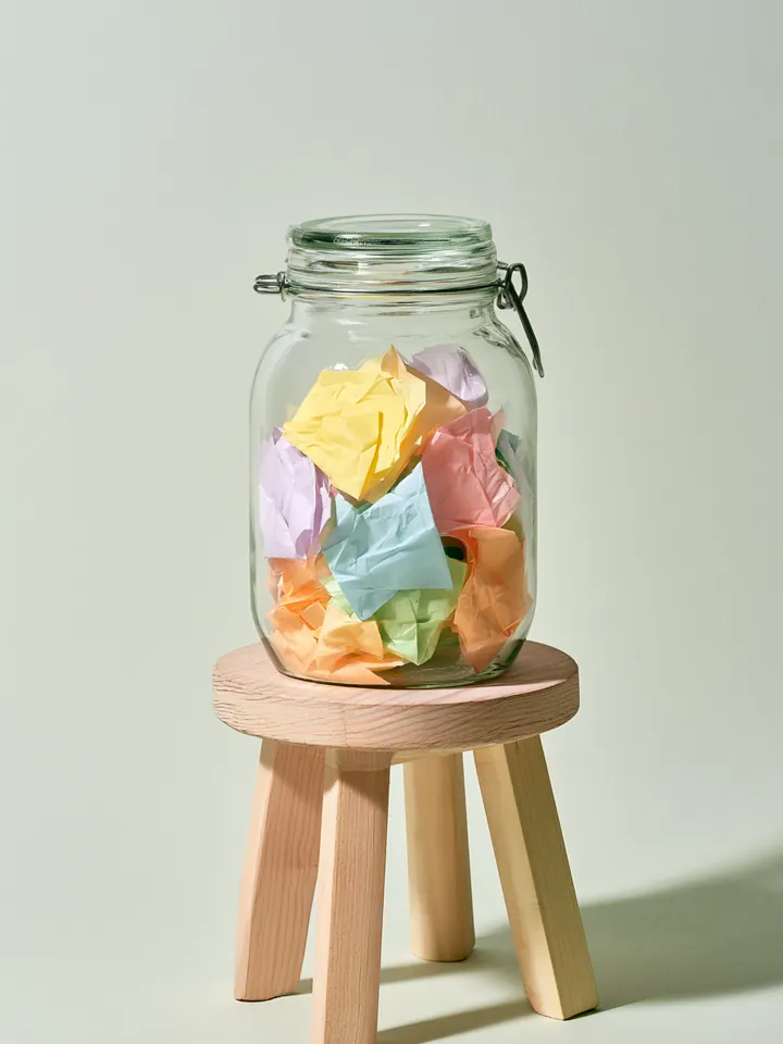 Glass jar filled with folded pastel notes, symbolizing a planned Happy Money loan budget