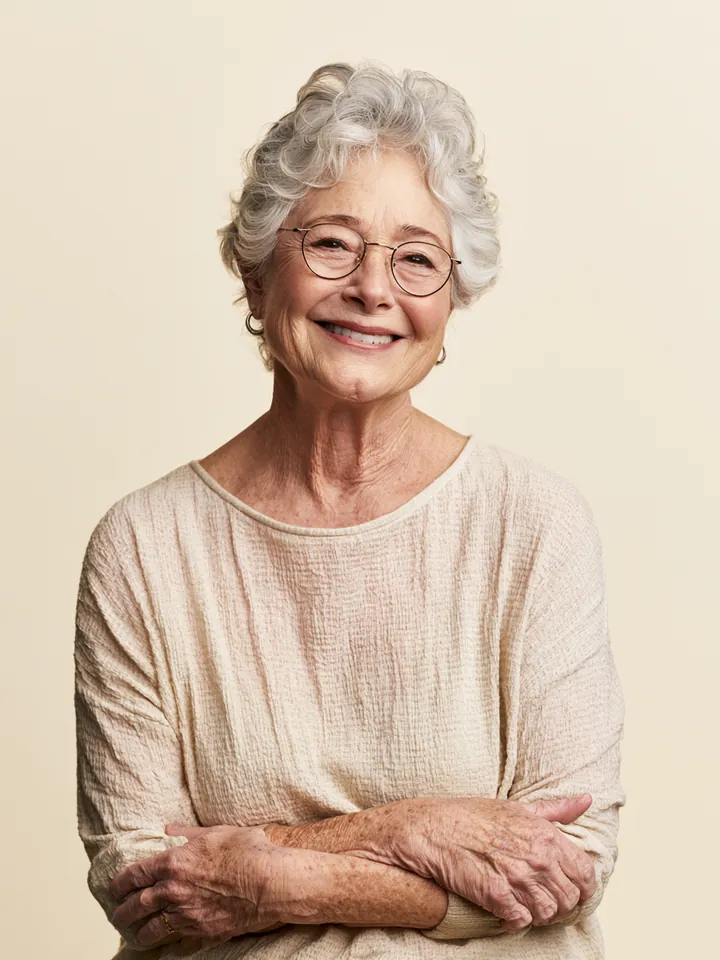 Elderly woman with silver hair and round glasses smiling warmly, representing a Happy Money reviews contributor